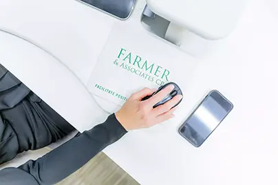 Aerial view using a computer mouse over a Farmer & Associates CPA mousepad on a pristine white desk, highlighting focused work and professional branding.